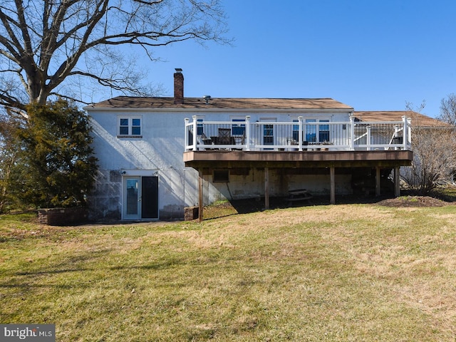 back of property with a deck, a lawn, and a chimney