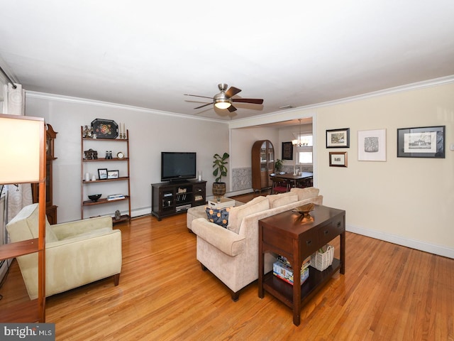 living area with a baseboard radiator, ceiling fan with notable chandelier, baseboards, light wood-style floors, and ornamental molding