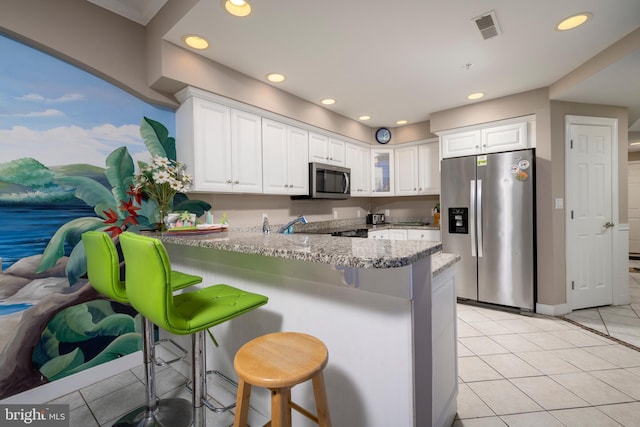 kitchen with stainless steel appliances, white cabinets, a peninsula, and light tile patterned floors