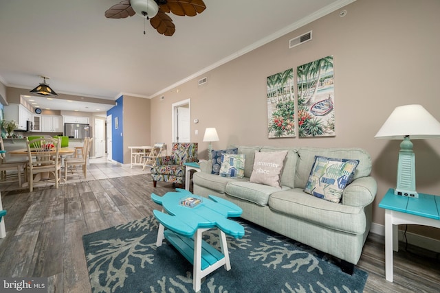 living room with baseboards, visible vents, ornamental molding, and wood finished floors