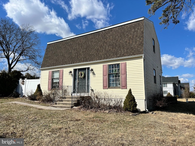 colonial inspired home featuring a shingled roof, fence, and a gambrel roof