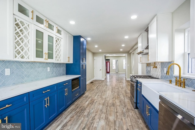 kitchen with white cabinetry, ventilation hood, stainless steel appliances, and blue cabinets