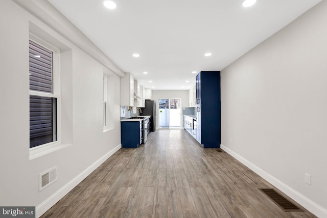 kitchen featuring blue cabinets, wood finished floors, and visible vents