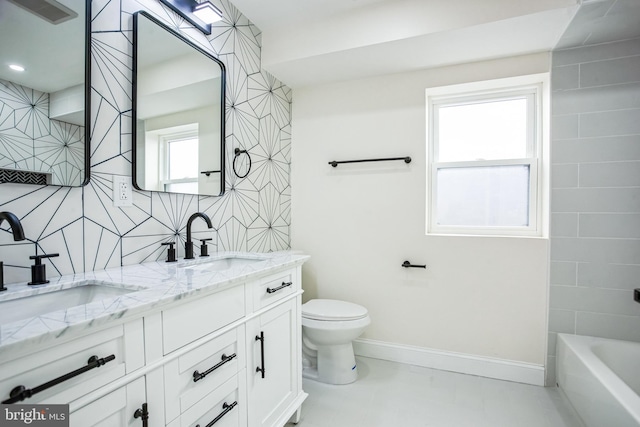 full bath featuring double vanity, toilet, baseboards, and a sink