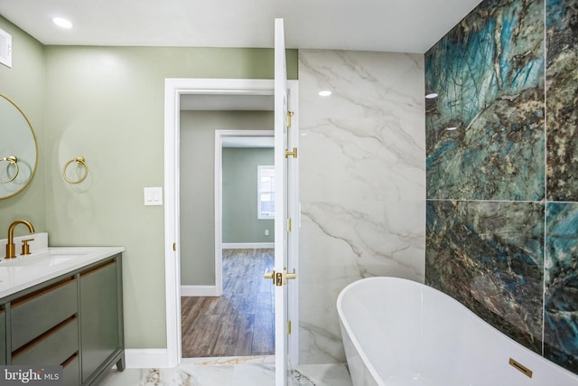 bathroom with vanity, baseboards, recessed lighting, a freestanding bath, and marble finish floor