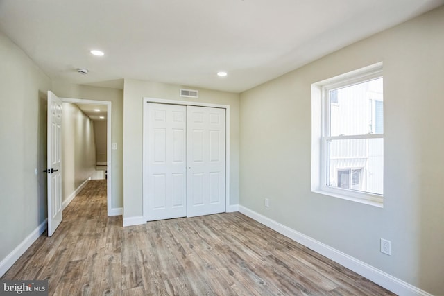 unfurnished bedroom featuring wood finished floors, visible vents, baseboards, recessed lighting, and a closet