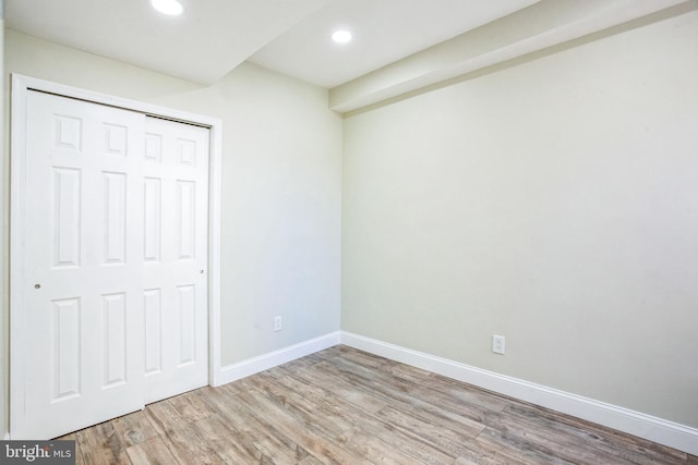 unfurnished bedroom featuring recessed lighting, wood finished floors, baseboards, and a closet