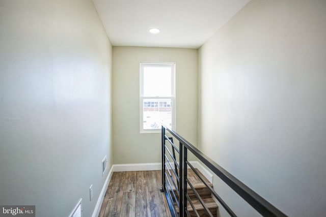 hall featuring dark wood-type flooring, an upstairs landing, baseboards, and visible vents