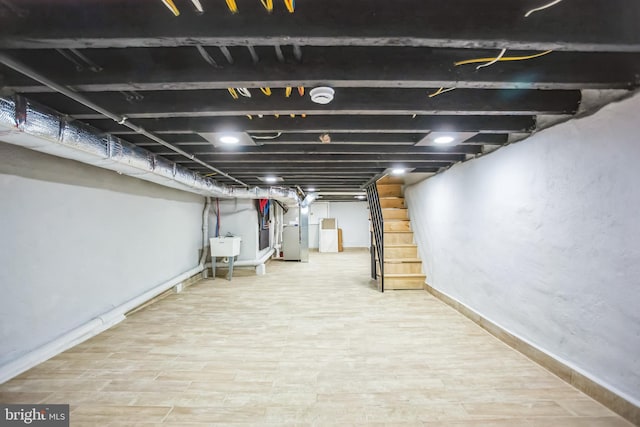 finished basement with a sink, heating unit, wood finished floors, and stairs