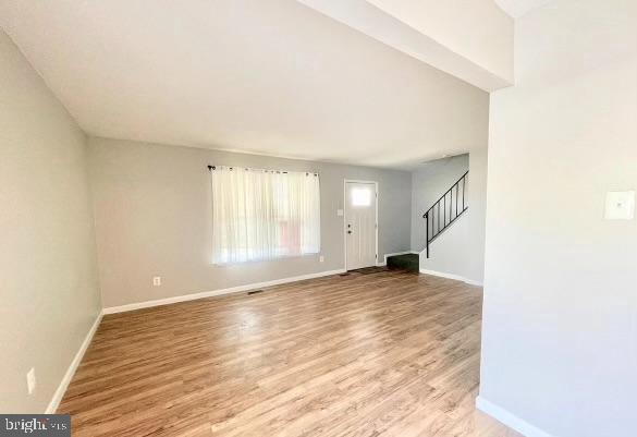 foyer entrance with light wood finished floors, stairs, and baseboards