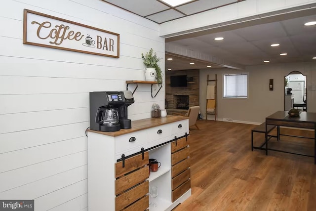 interior space featuring a drop ceiling, a fireplace, wood finished floors, arched walkways, and open shelves