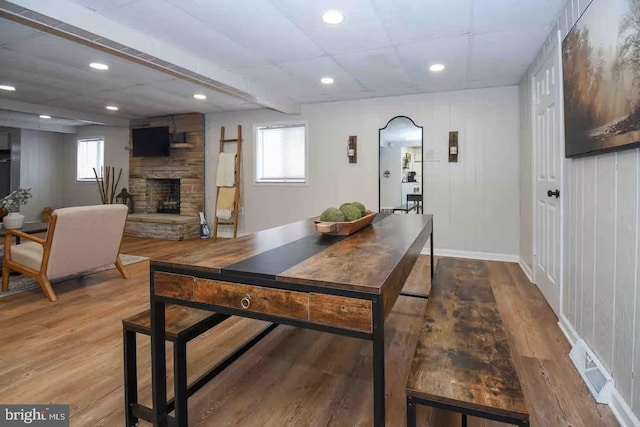 dining space with visible vents, recessed lighting, a stone fireplace, and wood finished floors