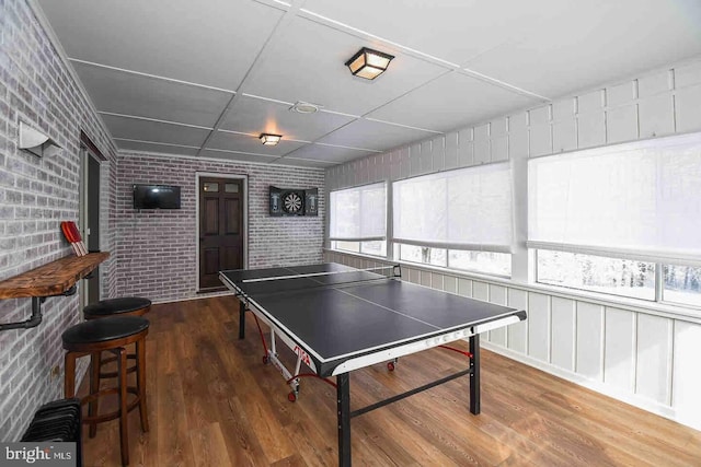 playroom with wood finished floors and brick wall