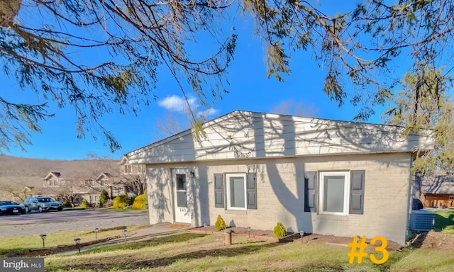 view of front of property featuring a front yard, central air condition unit, and brick siding