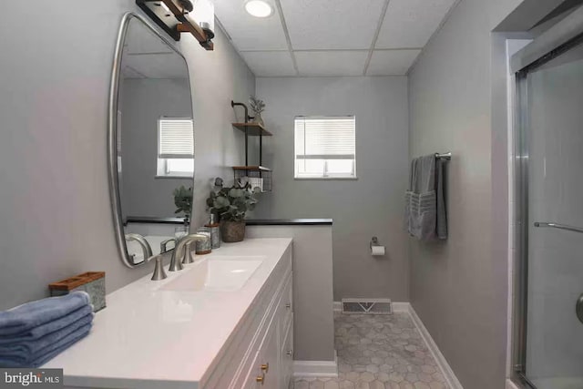 bathroom with a shower with shower door, a healthy amount of sunlight, visible vents, and a drop ceiling