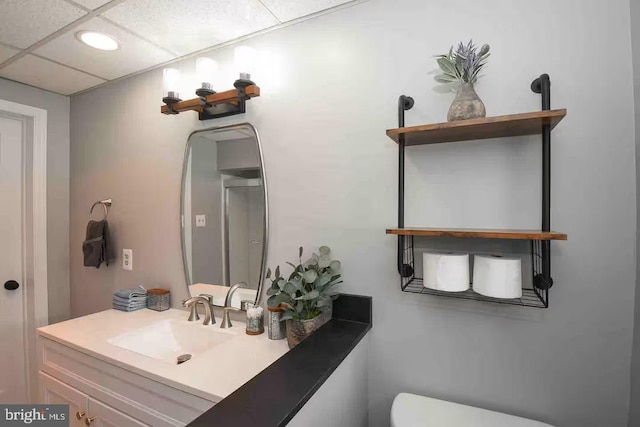 half bath featuring vanity, toilet, and a paneled ceiling