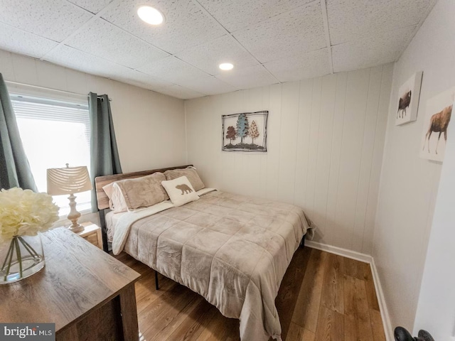 bedroom featuring baseboards, a paneled ceiling, and wood finished floors