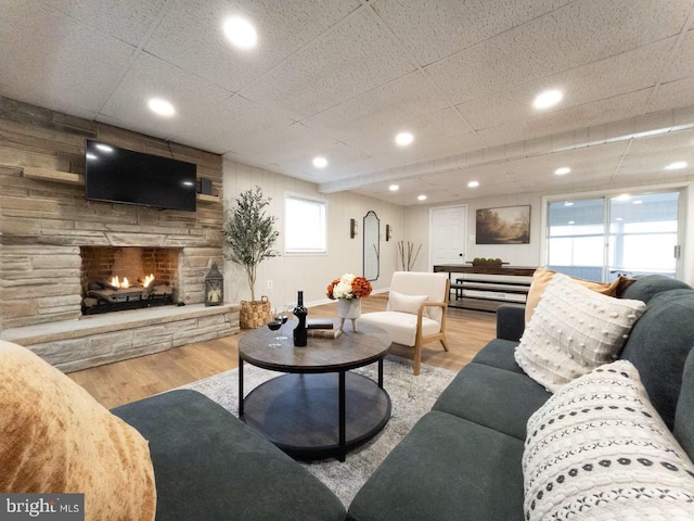 living room with a stone fireplace, recessed lighting, baseboards, and wood finished floors