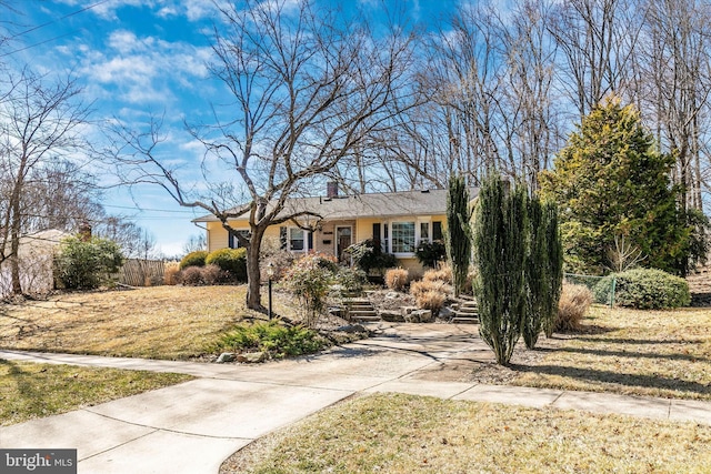 ranch-style home featuring concrete driveway, a chimney, and a front yard