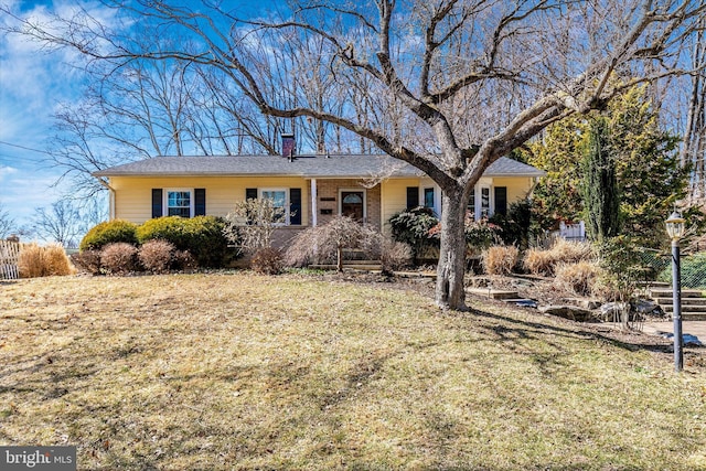 ranch-style house featuring brick siding, a chimney, and a front lawn