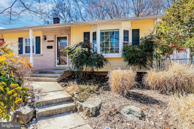 view of front of property with a chimney and brick siding