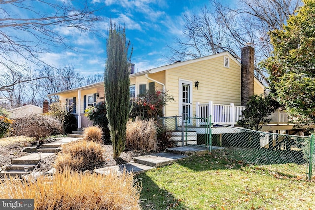 rear view of house featuring a chimney, fence, a deck, and a yard