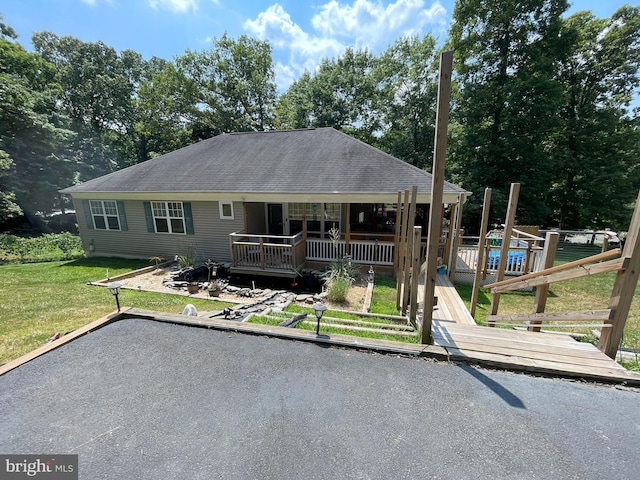 rear view of house with roof with shingles, a wooden deck, and a yard