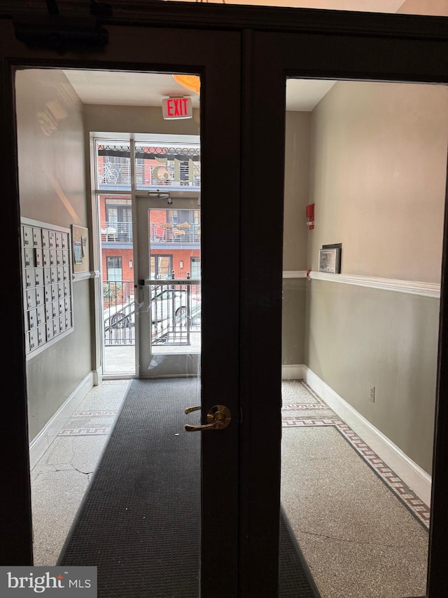 corridor featuring baseboards, carpet floors, and mail area