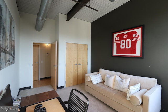 carpeted living room with a high ceiling, beamed ceiling, and baseboards