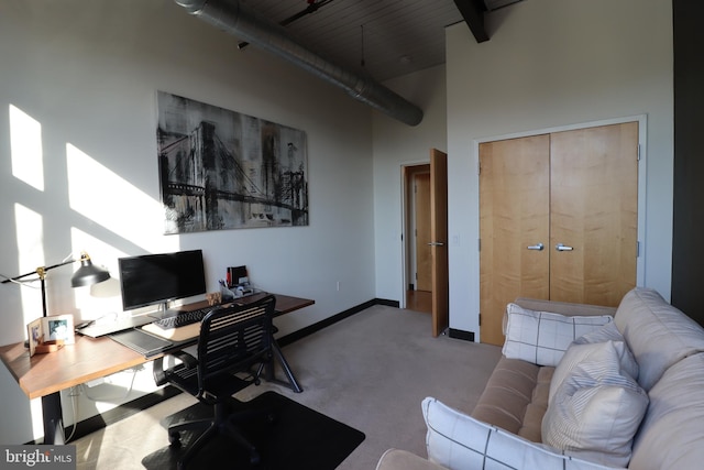 carpeted office featuring baseboards and a towering ceiling