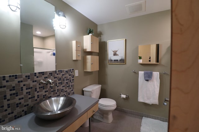 full bathroom with visible vents, toilet, a sink, backsplash, and walk in shower