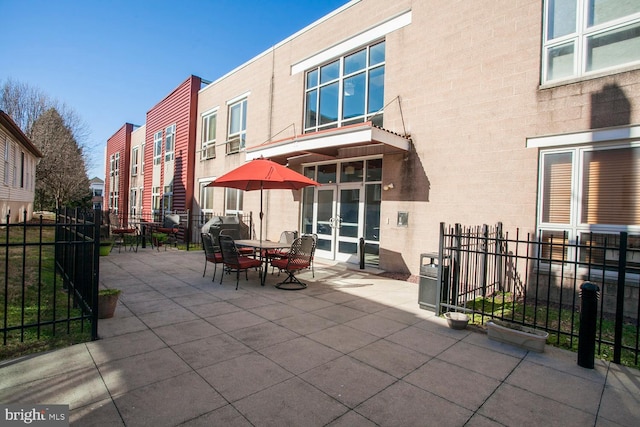 view of patio featuring french doors, a residential view, outdoor dining space, and fence