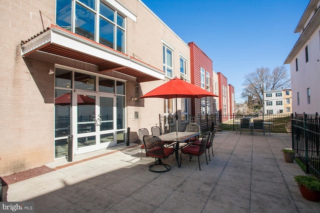 view of patio featuring french doors, outdoor dining area, and fence