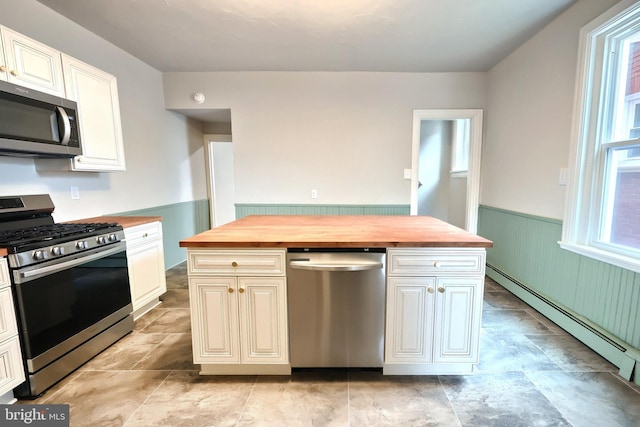 kitchen with wainscoting, butcher block counters, stainless steel appliances, and a baseboard heating unit