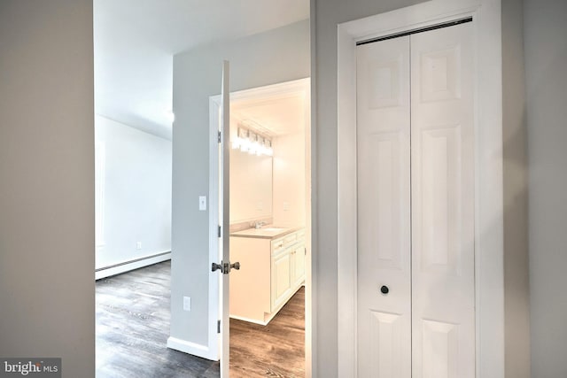 corridor featuring a sink, a baseboard radiator, and wood finished floors