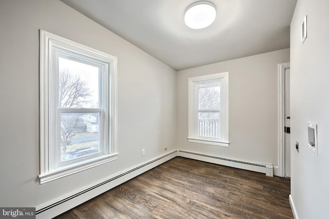 spare room featuring a baseboard heating unit and wood finished floors