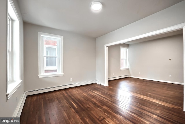 spare room featuring a baseboard heating unit, wood-type flooring, baseboards, and baseboard heating