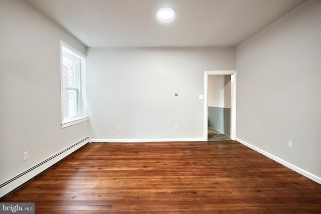 spare room featuring baseboards, baseboard heating, and wood finished floors