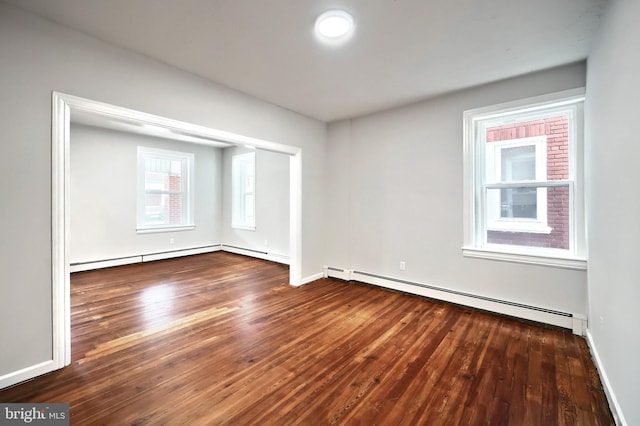 spare room with a baseboard heating unit, baseboards, and hardwood / wood-style floors