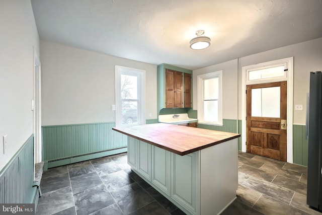 kitchen featuring stone finish floor, a wainscoted wall, wooden counters, and a baseboard radiator