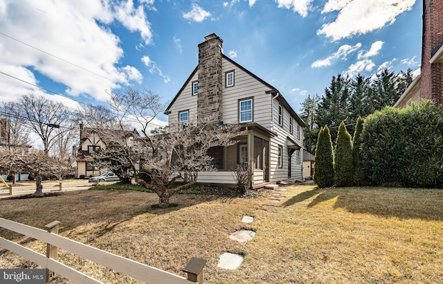 view of property exterior featuring a yard, a chimney, and fence