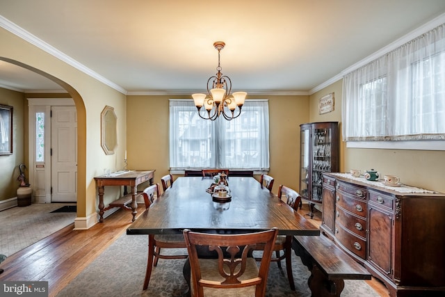 dining area featuring baseboards, arched walkways, a healthy amount of sunlight, and wood-type flooring