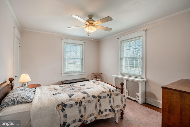 bedroom featuring ceiling fan, multiple windows, ornamental molding, and wood finished floors