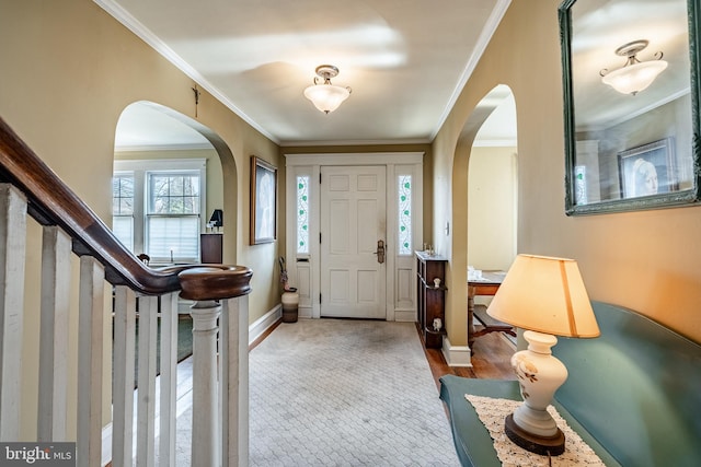 entryway with arched walkways, stairway, crown molding, and baseboards