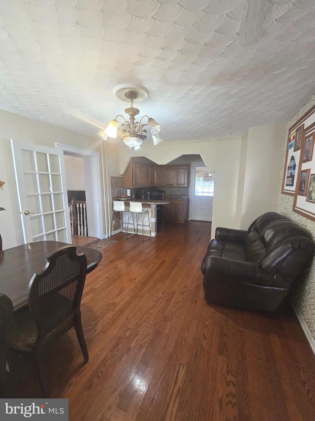 living area with a chandelier, dark wood-type flooring, and a textured ceiling