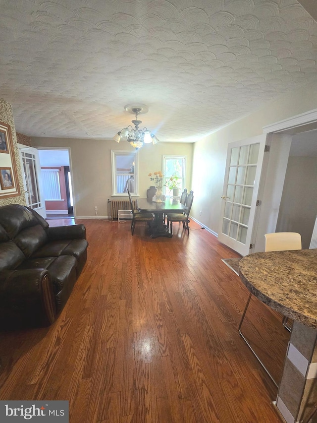 dining area featuring a textured ceiling, wood finished floors, and baseboards