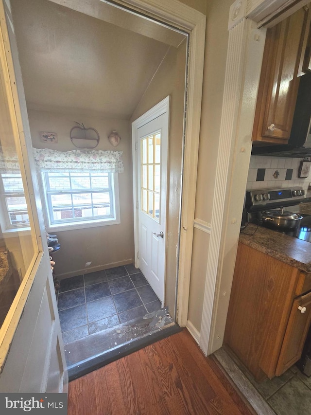 doorway to outside featuring lofted ceiling, dark wood-style floors, and baseboards