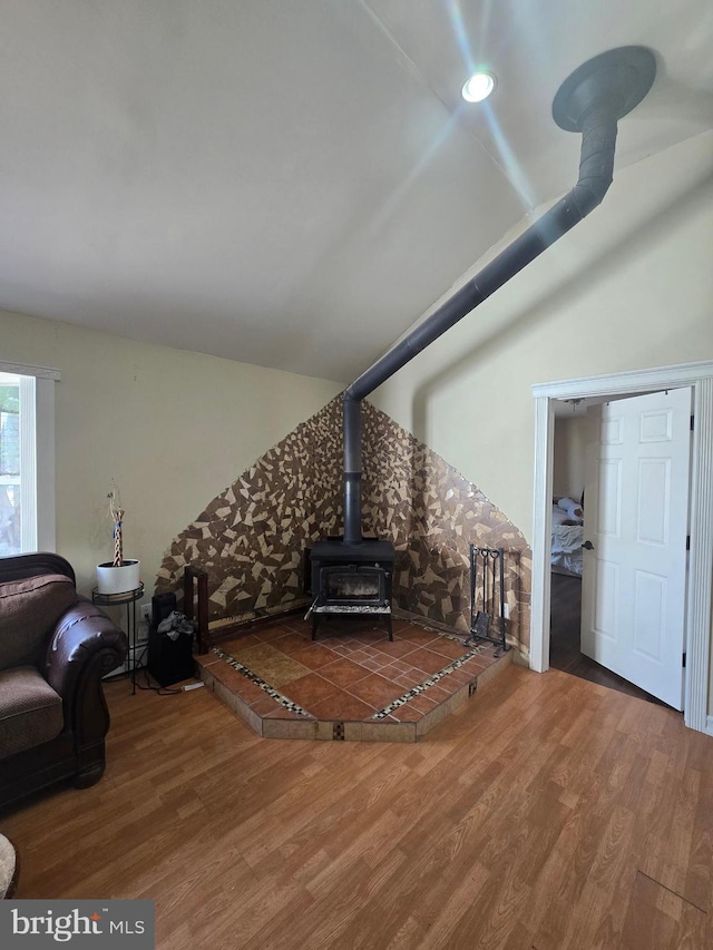 living area featuring a wood stove, wood finished floors, and lofted ceiling