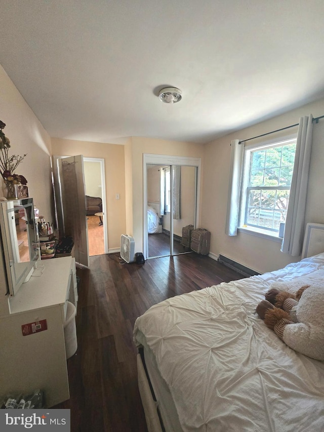 bedroom with baseboards, dark wood finished floors, and a closet