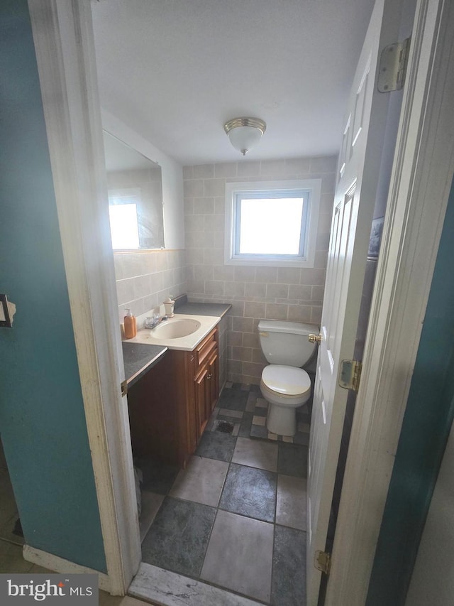 bathroom featuring tasteful backsplash, vanity, toilet, and tile walls